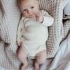 Vauva makaa peitolla yllään Vaniljan sävyinen Halaus Kietaisubody