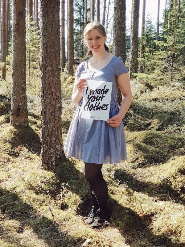 Fashion revolution, nainen seisoo metsässä kädessään lappu, jossa lukee I made your clothes