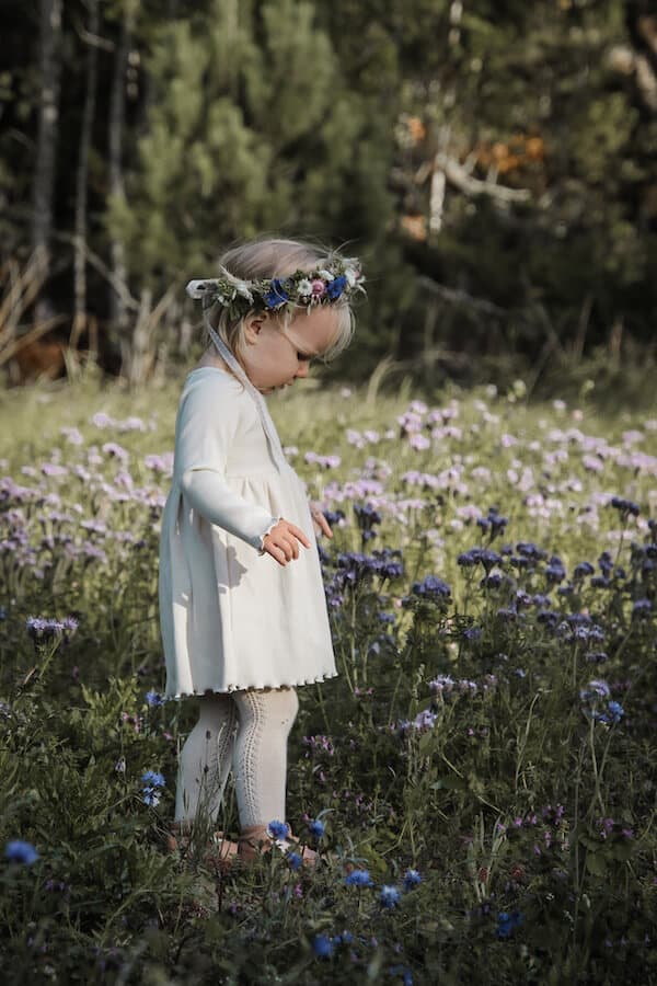 Tyttö kukkakedolla valkoisessa LEMPI mekossa kukkaseppele päässään