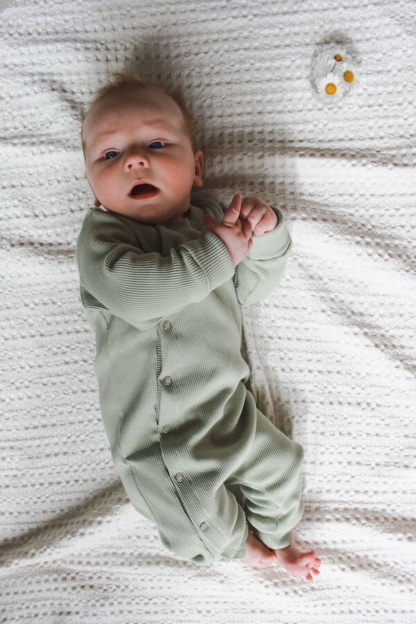 vauva valkealla peitolla yllään Sumunvihreä HENTO haalari