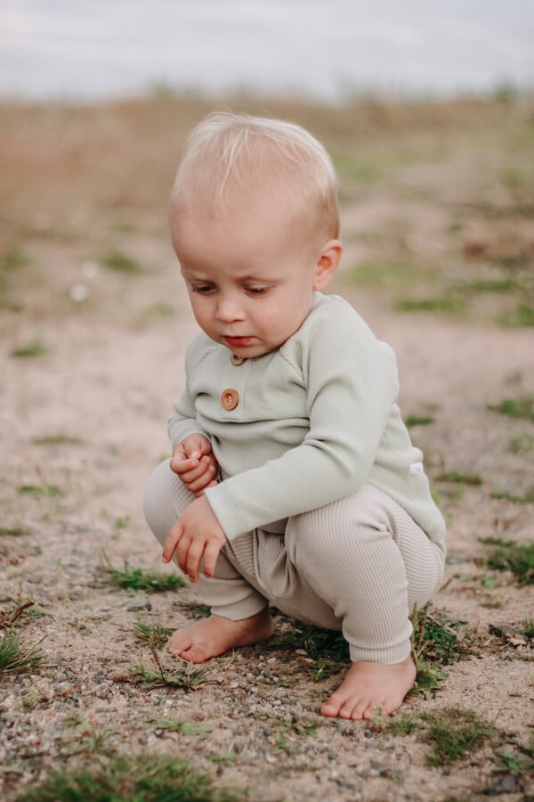 Poika tutkii hiekkaa vihreässä ribbi paidassaan